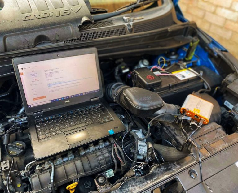 ESC Auto Electrics' laptop on the engine area of a car, performing car diagnostics